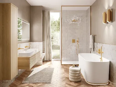 Ein helles Badezimmer mit weißen Waschbecken und hellen Badmöbeln aus Holz. Alle Armaturen sind gold