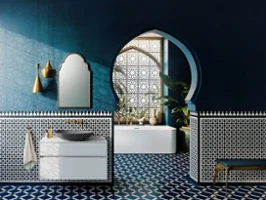 Une salle de bains élégante avec un sol carrelé géométrique bleu et blanc, un lavabo Loop & Friends gris et des miroirs décorés, complétés par des notes dorées et une plante verte.