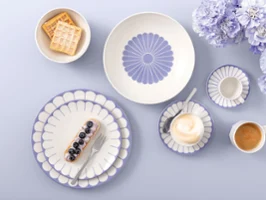 Table setting with Villeroy & Boch Fleur Bleu plates, coffee, dessert, waffles, and light purple flowers on a light background.