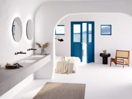 Une salle de bains lumineuse et moderne avec des murs blancs incurvés, une porte bleue, un lavabo Loop & Friends et des miroirs ronds More to See