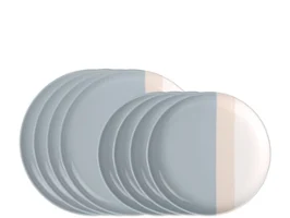 Un juego de platos, cuencos y tazas de cerámica con rayas de color gris claro y crema sobre un fondo gris.
