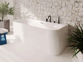 White Loop & Friends bath in front of a stone wall Modern bathroom with a freestanding white Loop & Friends bath in front of a textured stone wall with sunlight casting soft shadows