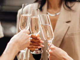 Trois personnes habillées dans des tons neutres portent un toast avec des flûtes à champagne NewMoon de Villeroy & Boch.