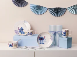 A placemat set with dishes, cups and bowls on the theme of "Stitch" on blue boxes, with striped gift box and decoration.