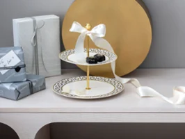  Eine MetroChic Etagere mit Gebäck umgeben von Geschenkboxen und einer Schleife auf einem Holztisch.