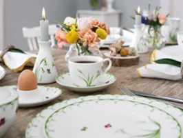Colourful Spring dinnerware on breakfast table with fresh flowers and candle Elegant table decoration with Colourful Spring dinnerware with floral patterns, fresh flowers and lit candle for a sophisticated meal.