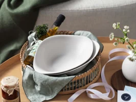 Vapiano plate in a basket, with an oil bottle on a wooden table, next to a vase and stationery from Villeroy & Boch