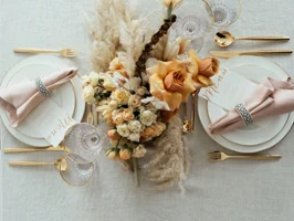 Elegant table decoration with gold MetroChic cutlery, Anmut crockery with a gold rim, a floral centrepiece and menu cards.