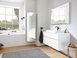 Un intérieur de salle de bain moderne avec des placards blancs, un grand miroir Finion, des doubles fenêtres et un sol en bois.