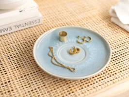 A Villeroy & Boch turquoise Crafted coffee cup saucer with gold jewellery on top.