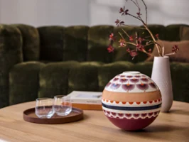 A La Boule Kyoto and a tray of glasses on a wooden coffee table in front of a green sofa.