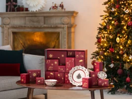 A festive living room with a decorated Christmas tree, a Villeroy & Boch advent calendar and Christmas-themed dishes on a wooden table.