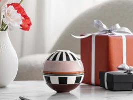 La petite Boule Memphis from Villeroy & Boch and two wrapped gifts stand on a marble table, with a vase of flowers in the background.