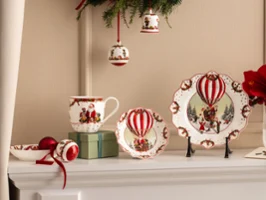 Annual Chistmas edition 2026 collection Festive ceramic plates, cups, and bowls with motifs of red hot air balloons from Villeroy & Boch are presented together with red flowers and Christmas decorations.