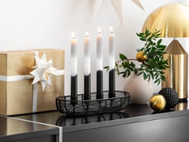 A Black Xmas Advent calendar with four candles A Black Xmas Advent calendar with four candles and a gold-wrapped gift with a white bow.