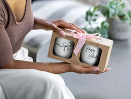 Person hält Geschenkbox mit rosa Schleife, darin zwei 'Happy Birthday'-Statement-Becher.