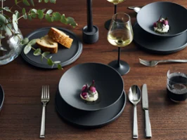 Iconic La Boule in black, arranged on a table setting with entree dish and bread, paired with silver cutlery and stemware, accented with vase with a simple floral arrangement.