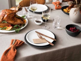 Thanksgiving dinner table with roast turkey, NewMoon wine glasses, Manufacture flatware and a plate with the phrase "Happy Thanksgiving".