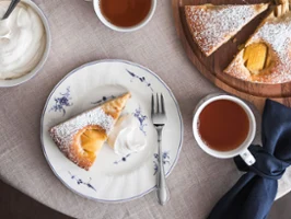 Vieux Luxembourg Geschirr mit Kuchenstücke mit Schlagsahne, Tee und Blumen auf einem Tisch.