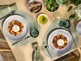 Deux assiettes de salade au fromage burrata, servies avec du pain, de la salade verte et un bol d'huile d'olive sur une table à manger.