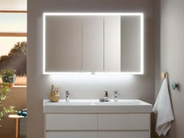 Un lavabo de salle de bains moderne avec une armoire de toilette rétroéclairée et des accessoires bien rangés