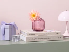 Mały szklany wazon Fleur na zielonej półce Różowy mały szklany wazon Fleur z kwiatem stoi na stosie książek na pastelowo zielonej półce.