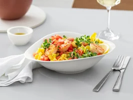 Vapiano Teller von Villeroy & Boch auf einem Holztisch gefüllt mit Nudelsalat. Auf dem Tisch stehend ein Weinglas und Besetck von Villeroy & Boch 