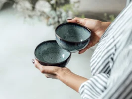 A person holding two ceramic bowls "Lave Gris" from Villeroy & Boch with a unique glaze.