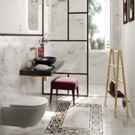 Une salle de bains moderne avec des murs et des sols en marbre, une baignoire en îlot, un plan double et des notes dorés.