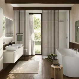 Une salle de bains minimaliste disposant d’une grande baignoire « Oberon 2.0 », d’un plan double « Finion » avec des lavabos « Artis » et d’une armoire de rangement en hauteur. Des notes de bois et des murs de couleurs neutres complètent la pièce.