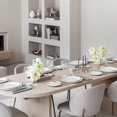 Side view of a table set with Afina crockery and Piemont cutlery in a beige-coloured room.