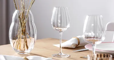 Elegant table decoration with a clear Rose Garden wine glass, a vase with dried stems and fine crockery.