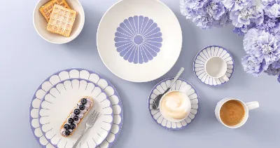 Table setting with Villeroy & Boch Fleur Bleu plates, coffee, dessert, waffles, and light purple flowers on a light background.