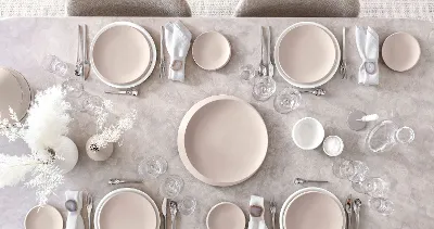 A table set with Villeroy & Boch NewMoon plates in beige and white along with cutlery and glasses.