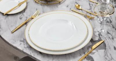 A white and gold dinnerware set from Château Septfontaines on a marble table.