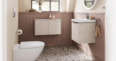 Łazienka dla gości z ceramiką i meblami z kolekcji łazienkowej Subway 3.0 firmy Villeroy & Boch Łazienka z oknem, żwirową podłogą, wiszącą umywalką i toaletą. Nad umywalką znajduje się okrągłe lustro, w dolnej części na ścianach drewniana boazeria, a w górnej części ścian oprawione obrazy.