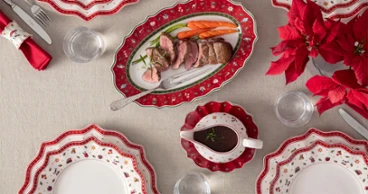 Toy's Delight meat fork Festive table decoration featuring red and white plates, a roast, carrots, a sauce boat and a red poinsettia as a centrepiece.