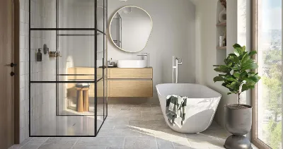 A white Theano Curved Edition bath in a light-coloured bathroom with a floor-to-ceiling window.