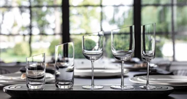 New Moon Glasses on tray Five empty glasses of different shapes are lined up on a table in front of a window.