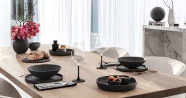 La Boule w czarnym kolorze z kieliszkami Manufacture i sztućcami Piemont Stół jadalniany z drewna nakryty czarną La Boule, kieliszkami Manufacture i sztućcami Piemont marki Villeroy & Boch.
