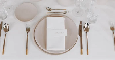 A table at a wedding reception set with NewMoon crockery and glasses A festive table setting with white and beige NewMoon plates, Ella cutlery and NewMoon glasses.