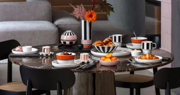 Elegant breakfast with Memphis by Villeroy & Boch A round breakfast table set with croissants, fruit, coffee and black and white striped crockery from the Memphis collection by Villeroy & Boch.