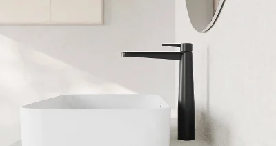 Lavabo da bagno minimalista con bacino rettangolare bianco e rubinetto alto nero fissato su un piano beige. 