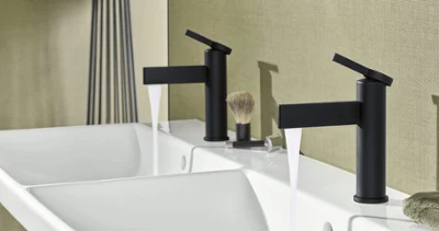 Black Dawn washbasin tap with an Avento washbasin A modern bathroom with two black taps above a white washbasin. On the shelf there is a shaving brush and a towel.