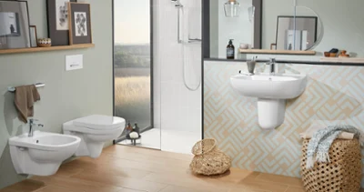 Nowoczesna łazienka z WC, bidetem, umywalką i prysznicem z kolekcji O.novo Nowoczesna łazienka z beżowymi kafelkami i pastelowymi ścianami wyposażona jest w wiszącą miskę WC O.novo, bidet, umywalkę z lustrem i prysznic zlicowany z podłogą. Na półkach znajdują się oprawione dzieła sztuki i przybory toaletowe. Na podłodze stoją kosze.