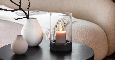 A Manufacture candle standing on a table next to two Manufacture vases.