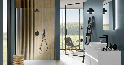 Black Universal Showers shower tap in a petrol-coloured bathroom with large windows and a washstand.