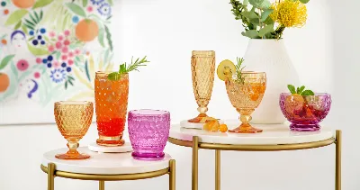 Colourful summer drinks in various Boston glasses on a stylish serving table with a flower painting in the background.