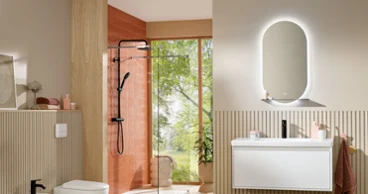 A stylish beige bathroom featuring the Skyla bidet, toilet, and washbasin, complemented by a terracotta accent wall in the shower area. The More To See Lite illuminated mirror adds modern functionality and soft, ambient lighting.