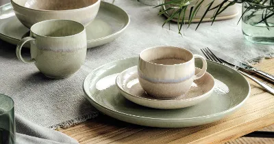 Rustic table decoration with Perlemor plates and cups in subtle earthy colours on a wooden table.